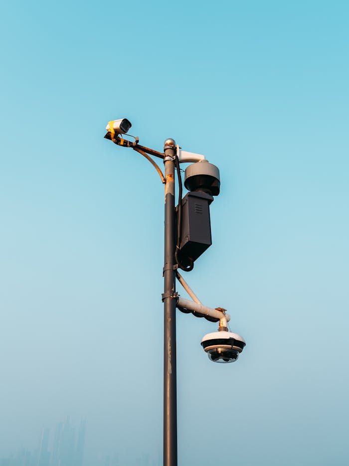 Surveillance cameras mounted on a pole against a clear sky, symbolizing modern urban security measures.